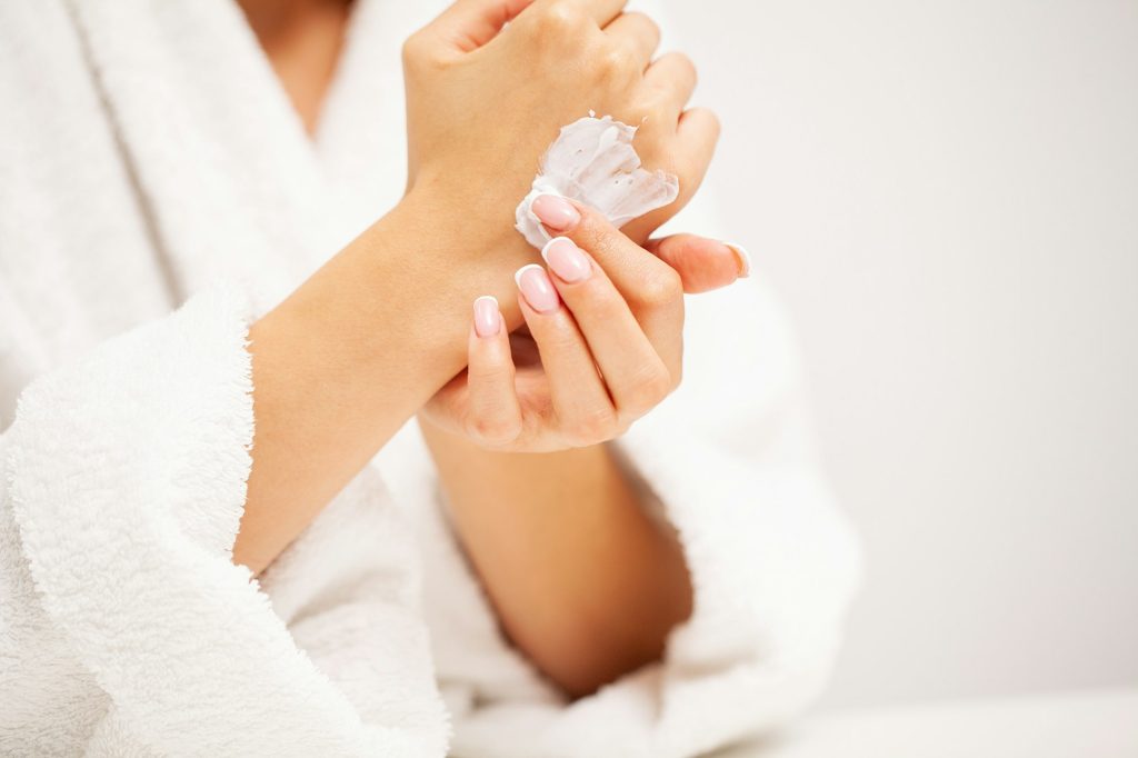 Woman applies moisturizer cream for hand skin care