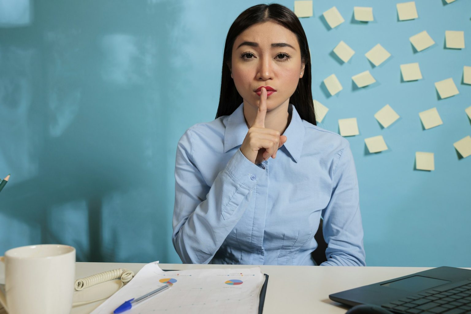 Woman making silence gesture at work