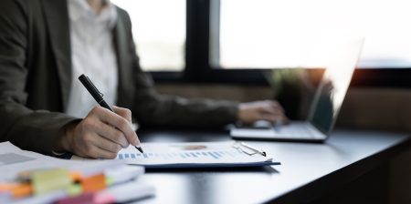 Businesswoman hand analyzes profitability of working companies with graph chart.