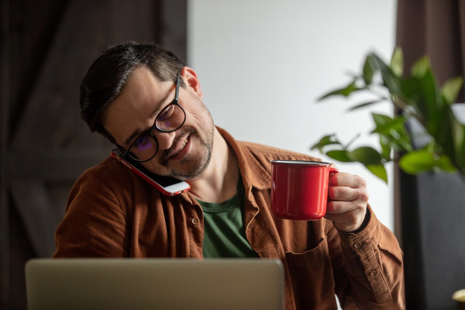 Tired developer working with laptop, drink coffee and calling by mobile phone at home