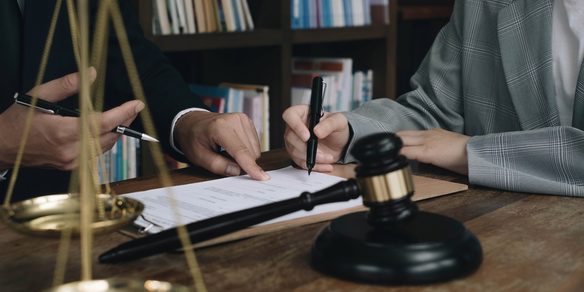 Business woman and lawyers discussing contract papers with brass scale on wooden desk in office. Law