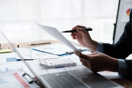 Pourquoi les services fiduciaires sont essentiels pour la gestion de votre entreprise ? Businessman working with business report papers on office desk, financial chart analysis with calcul