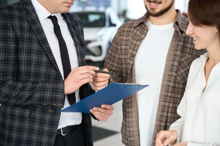Couple signing some documents with salesperson or manager buying or renting car