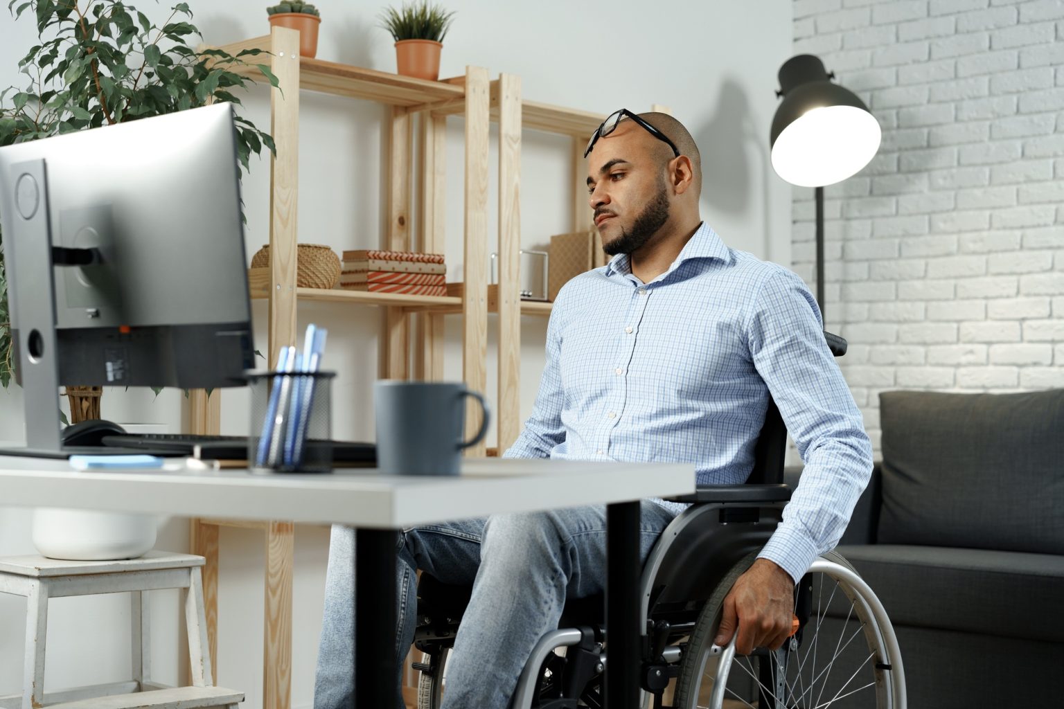 Disabled african american man sitting at the table and working on computer