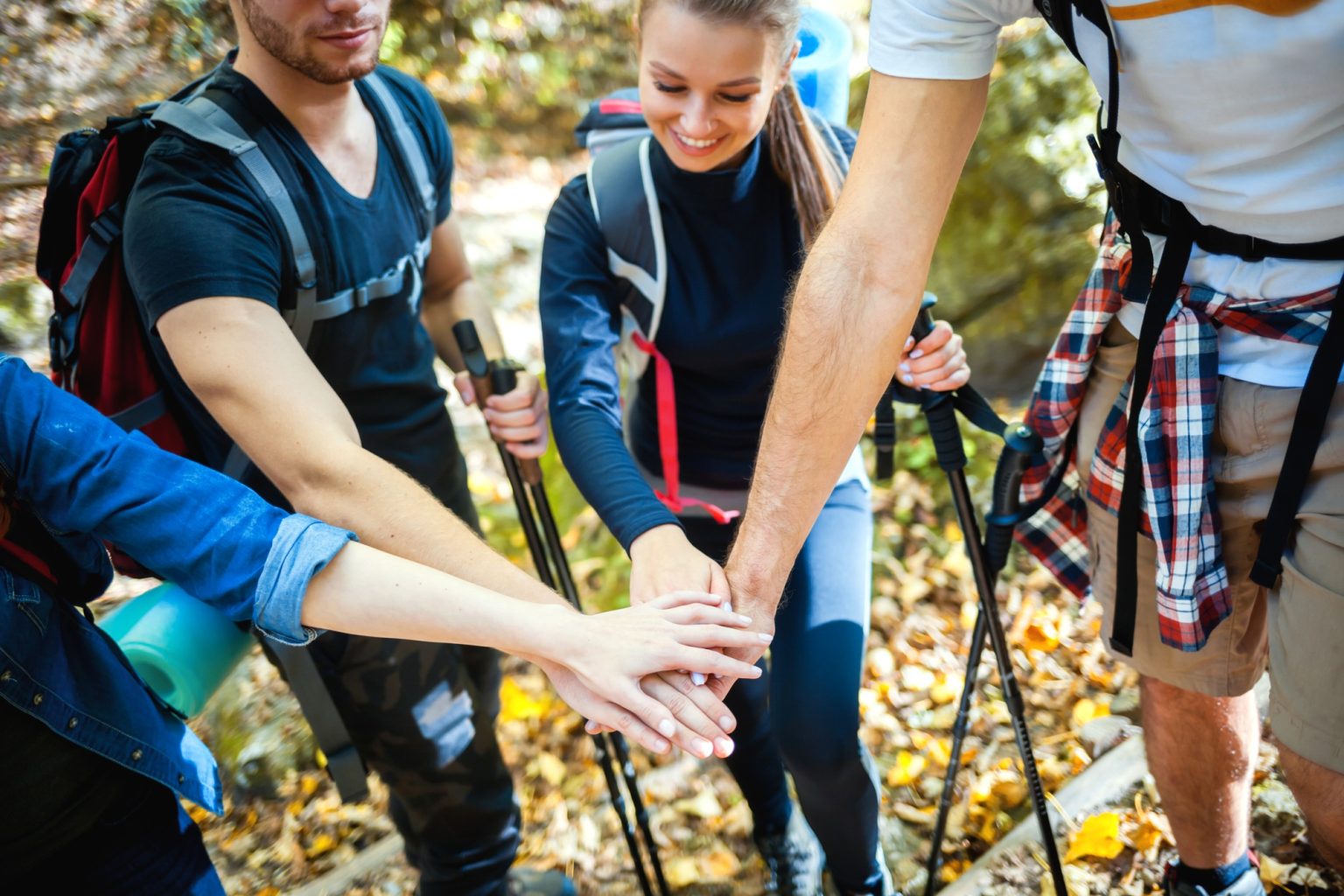 Group of friends stacking hands before climb on the mountain trail, motivation during trekking