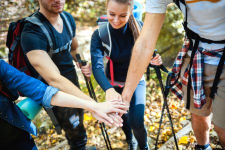 Group of friends stacking hands before climb on the mountain trail, motivation during trekking