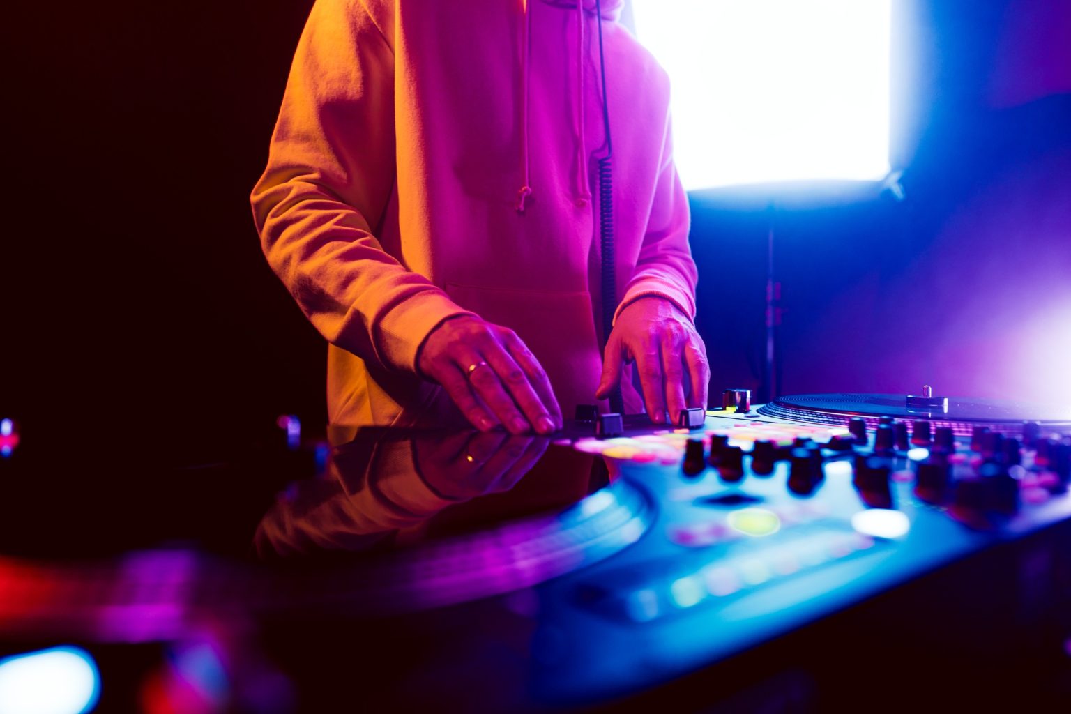 Hands of a DJ creating and regulating music on dj console mixer at club concert