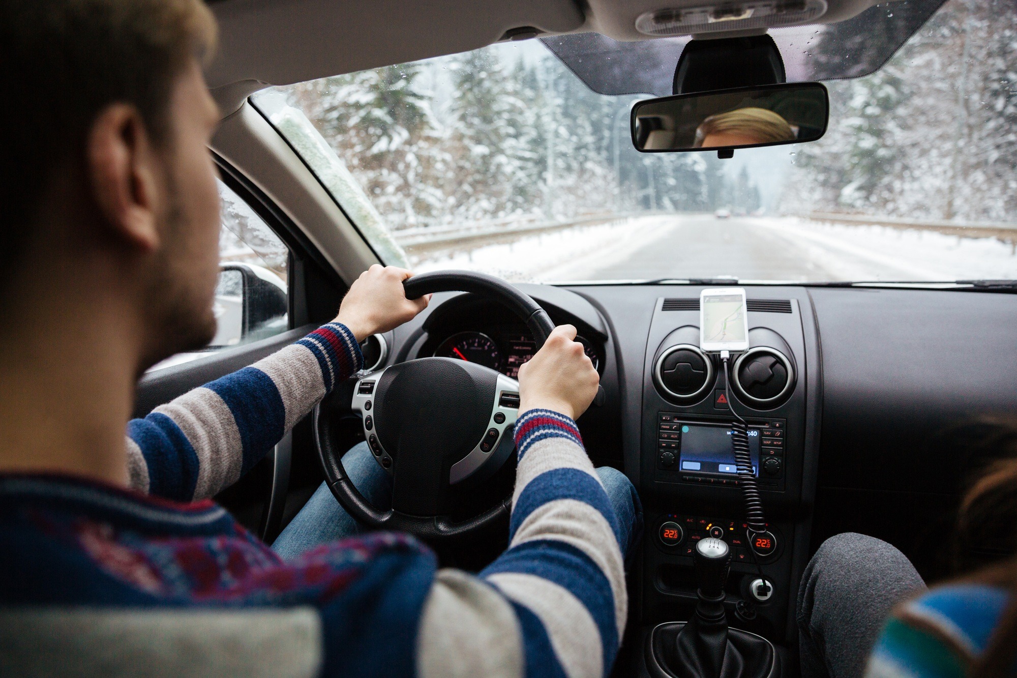 Handsome young driver driving through winter forest