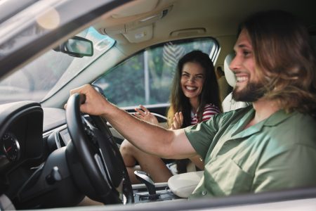 Happy couple enjoying a car ride, sharing smiles and laughter, with a bright interior and greenery