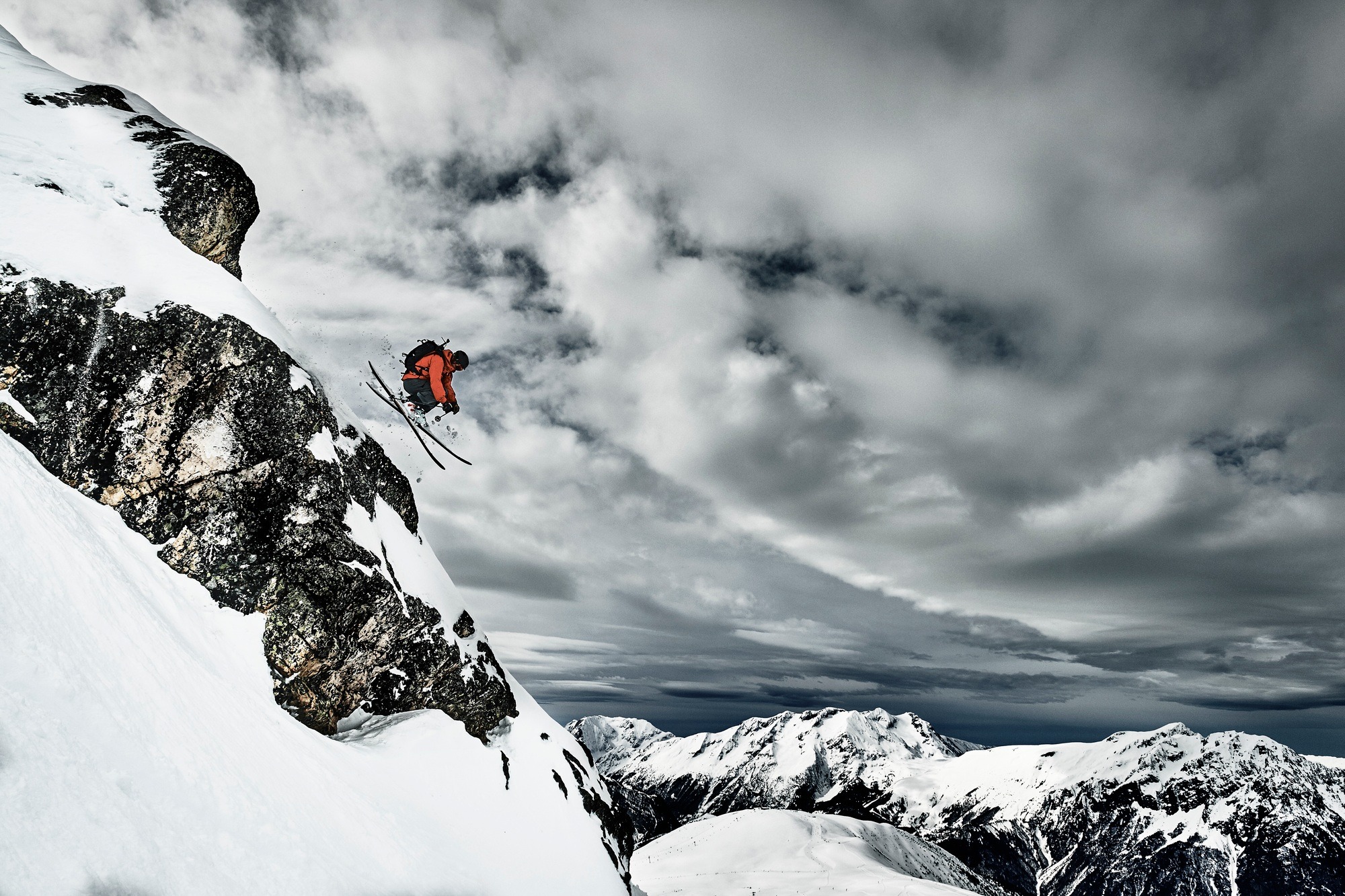 Male skier jumping mid air from rugged mountainside, Alpe-d'Huez, Rhone-Alpes, France