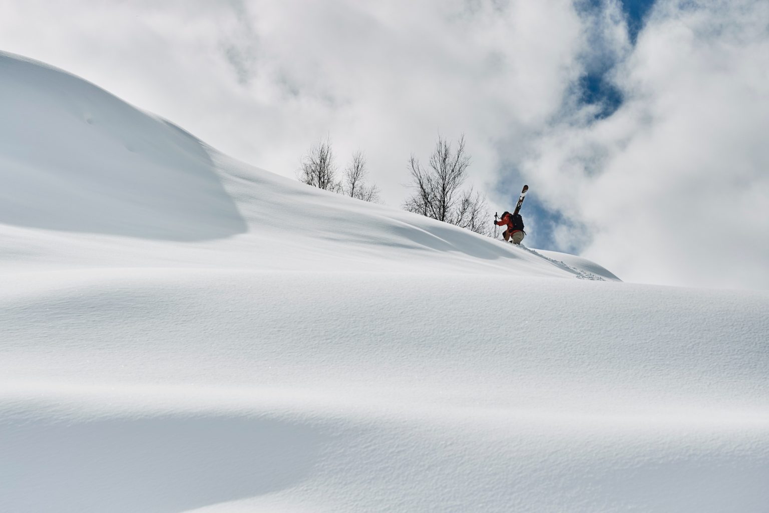 Male skier trudging up snow covered mountain, Alpe-d'Huez, Rhone-Alpes, France