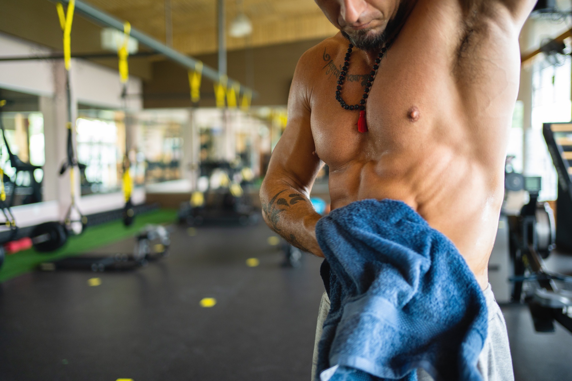 Strong man in a gym drying himself with a towel