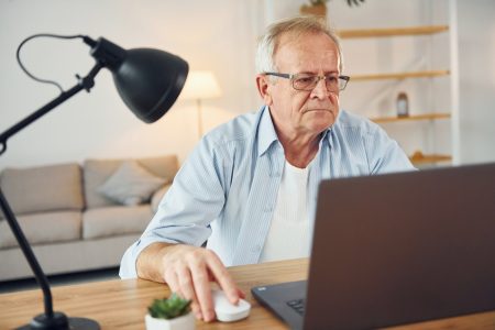 With laptop on table. Senior man in nice clothes is at home
