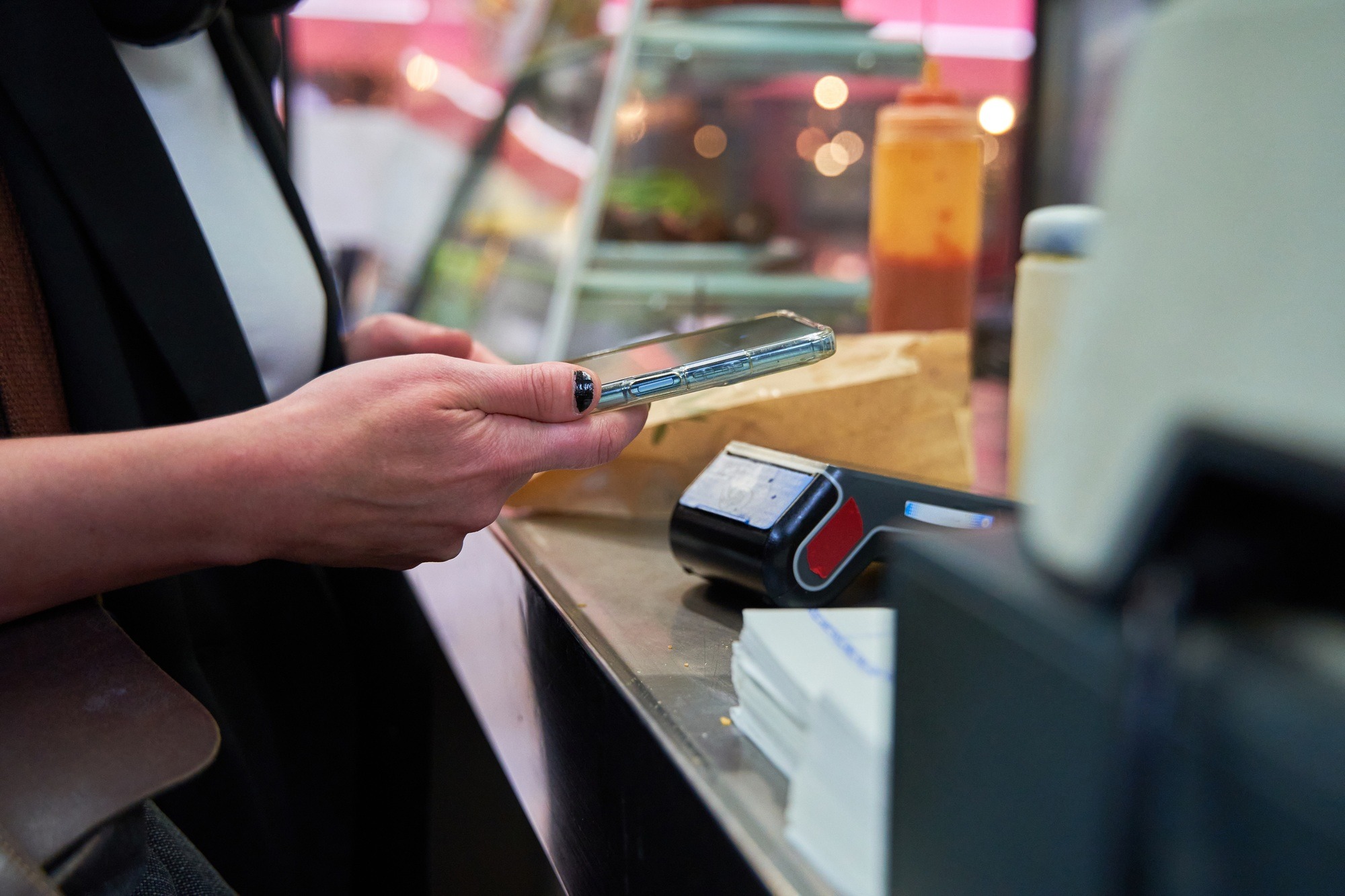 A woman is using her cell phone to pay for food at a restaurant.