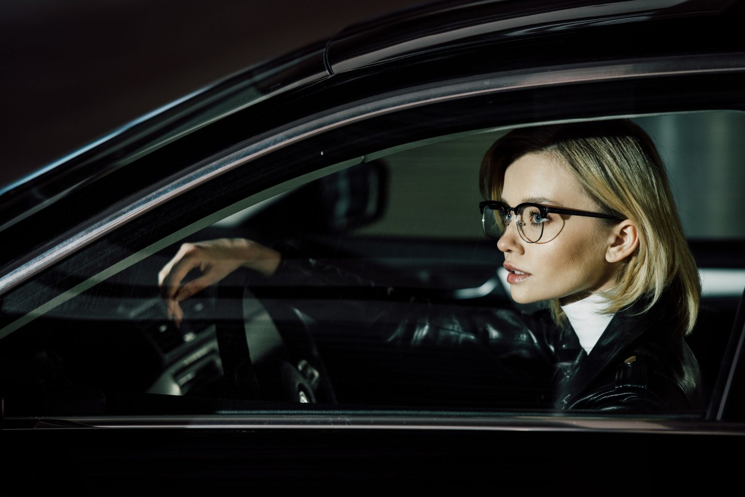 attractive blonde woman in glasses sitting in car