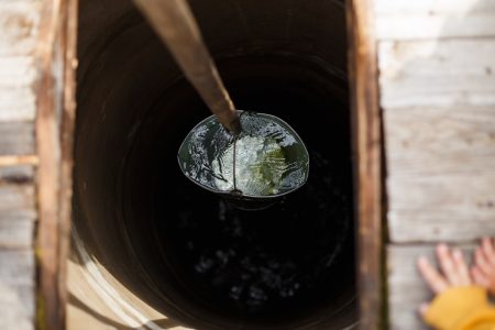 Blue bucked inside water well. water well with an old iron bucket