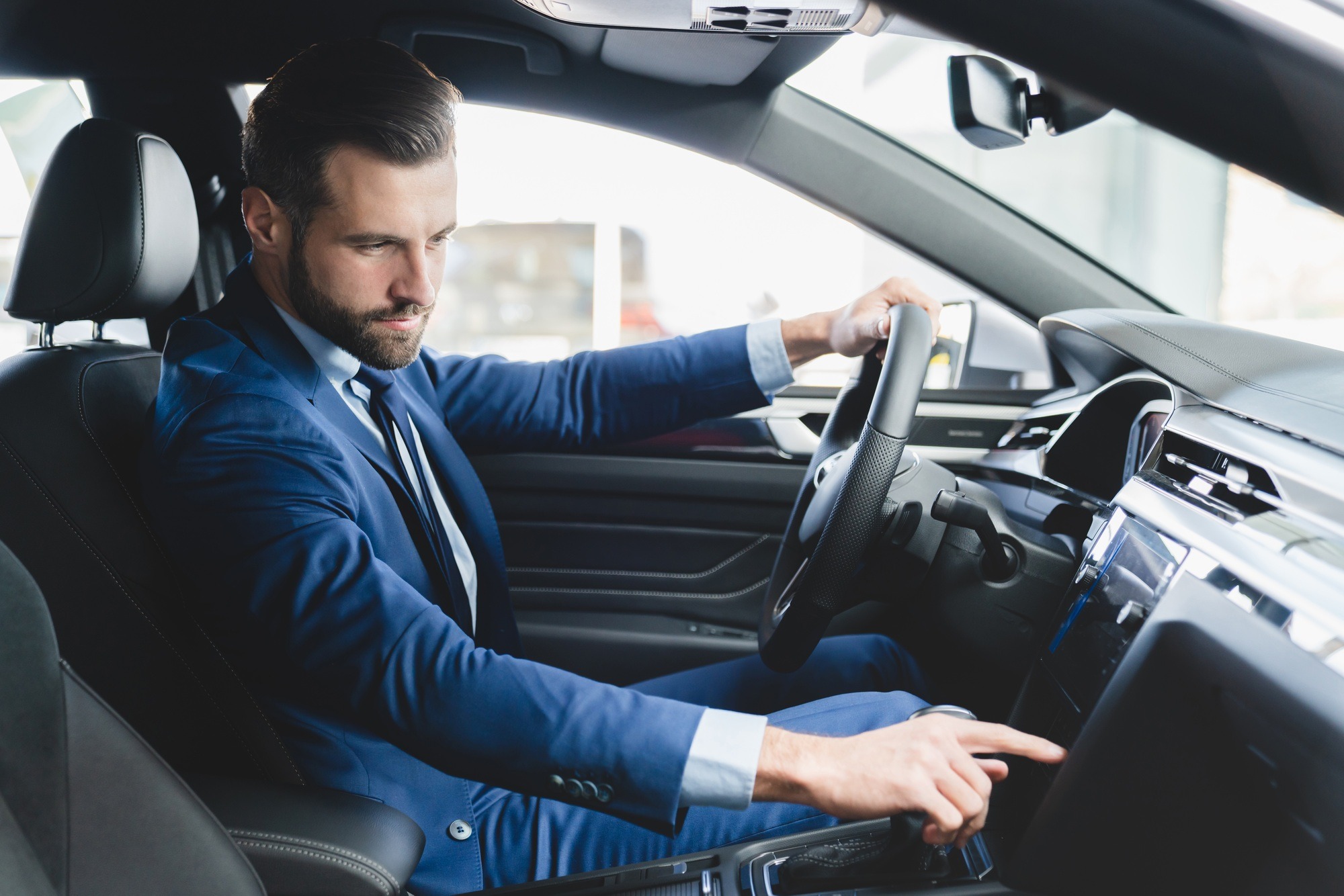 Businessman trying checking new car starting engine before buying it at automobile dealer shop
