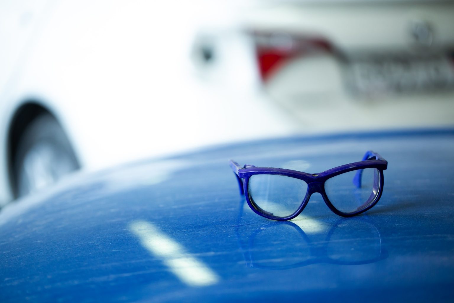 Car mechanic's safety glasses on the blue hood