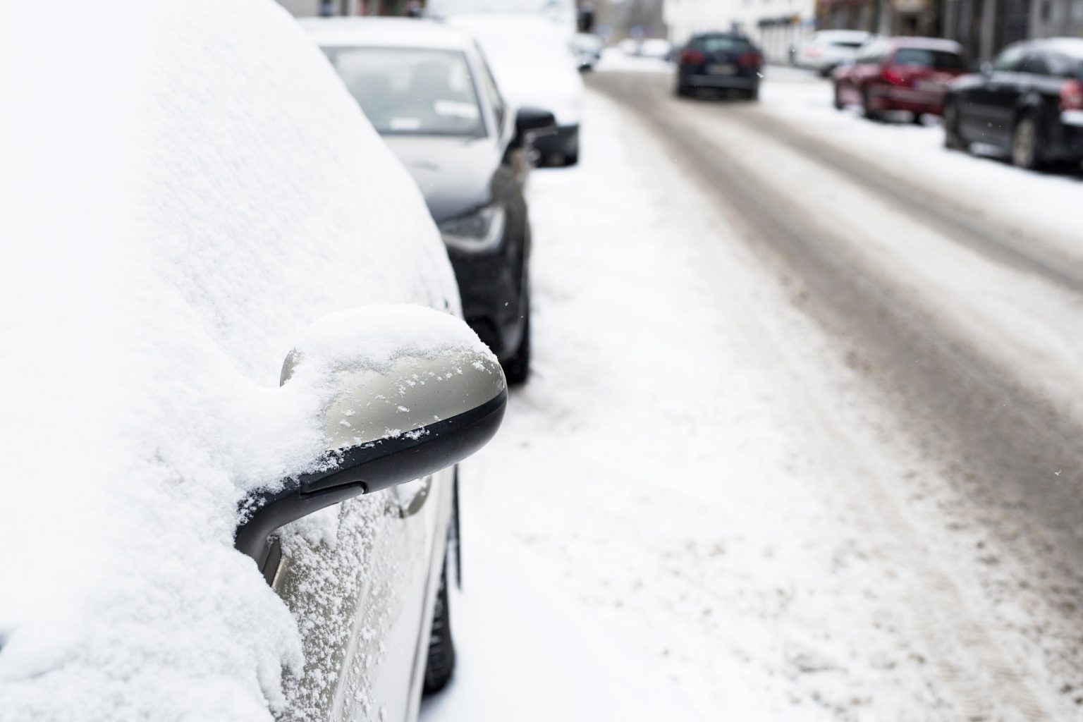 Cars covered with snow on city street