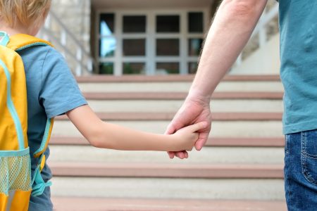 Little schoolboy with his father goes to school after summer holiday.