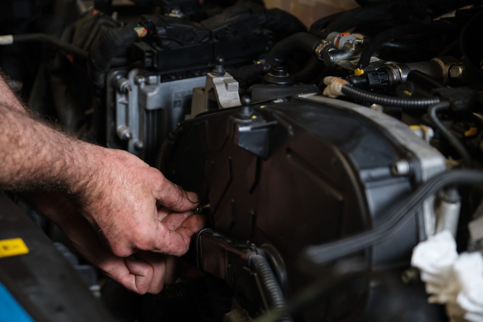 Auto mechanic hands unscrews the engine mount to replace the timing belt.