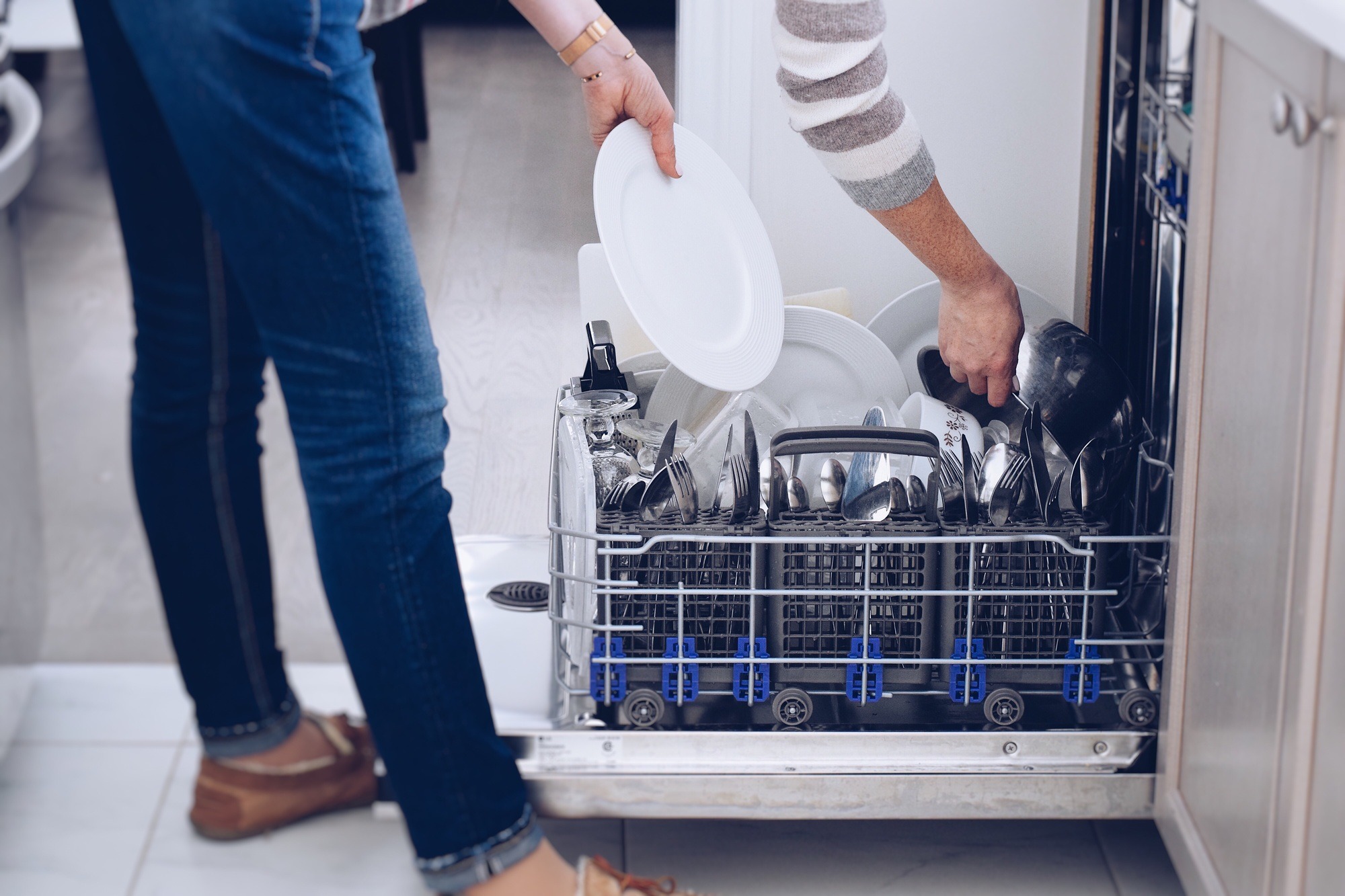 Woman unloading clean dishes from a dishwasher