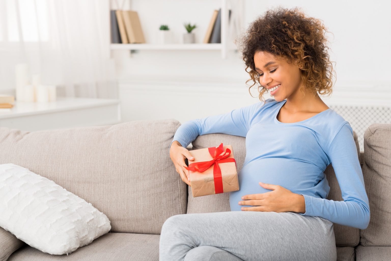 Happy pregnant african-american woman with gift box