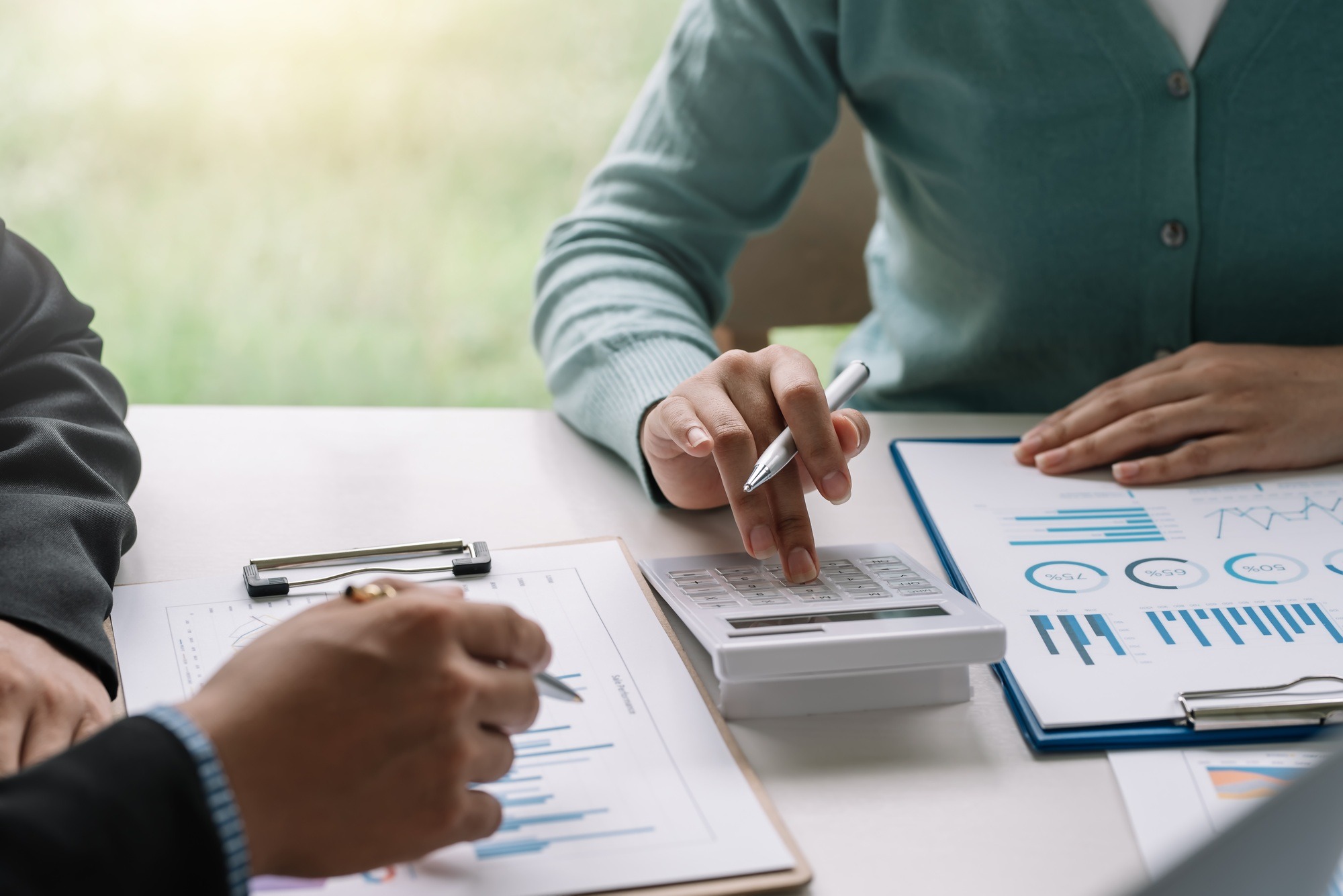 Close-up of a group of businessman and businesswoman hands brainstorming together using graph calcul