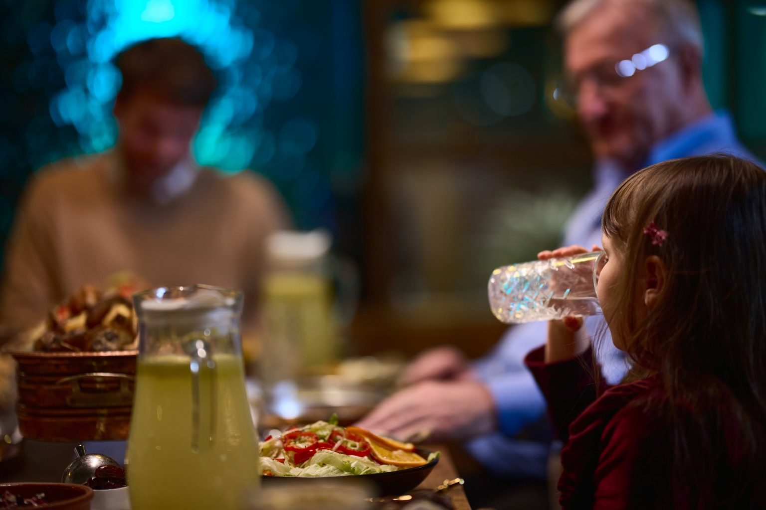 In a modern restaurant, a young girl participates in iftar by breaking her fast with water