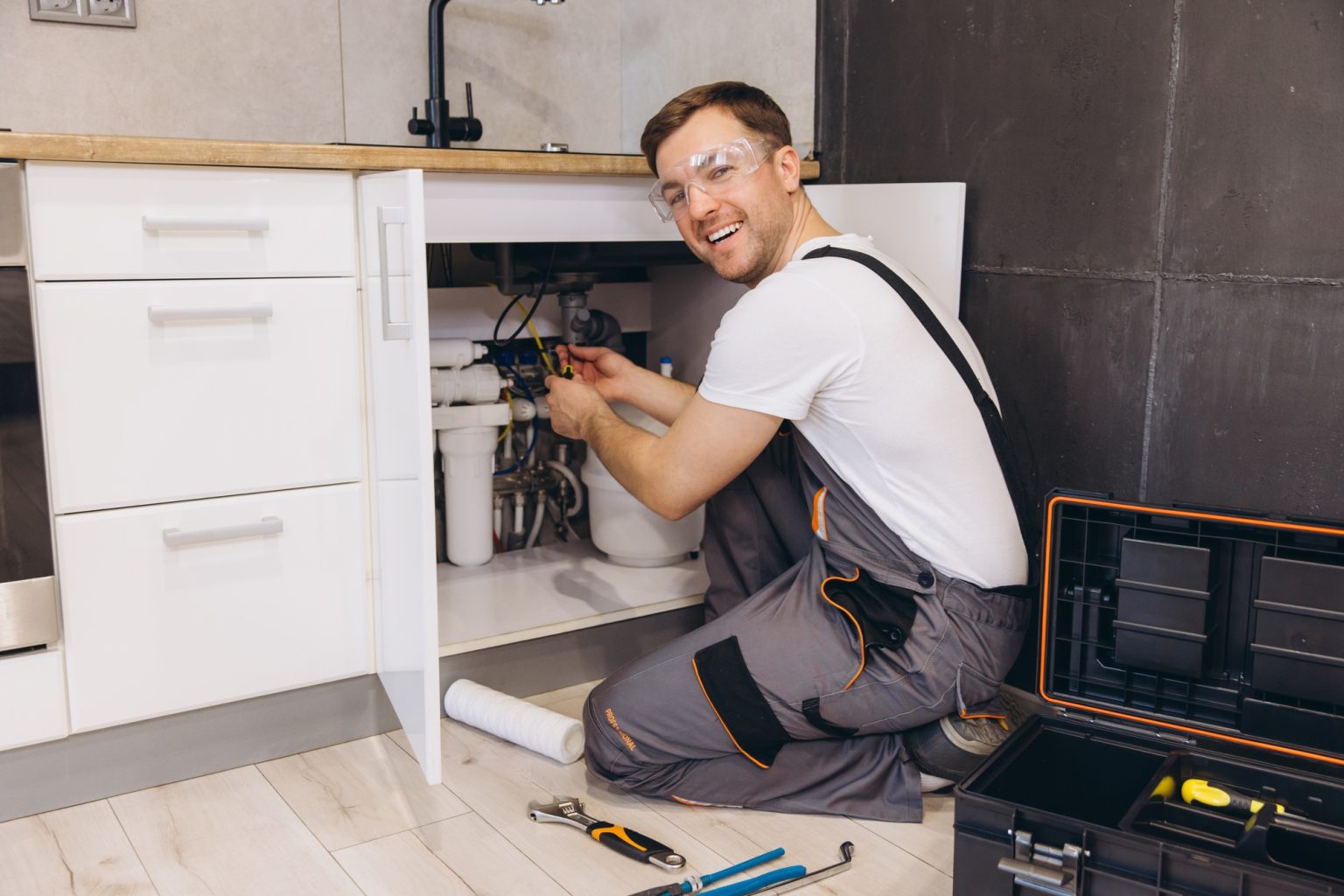 Plumber installing water filter system under kitchen sink