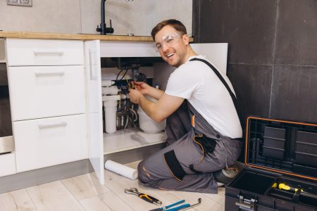 Plumber installing water filter system under kitchen sink