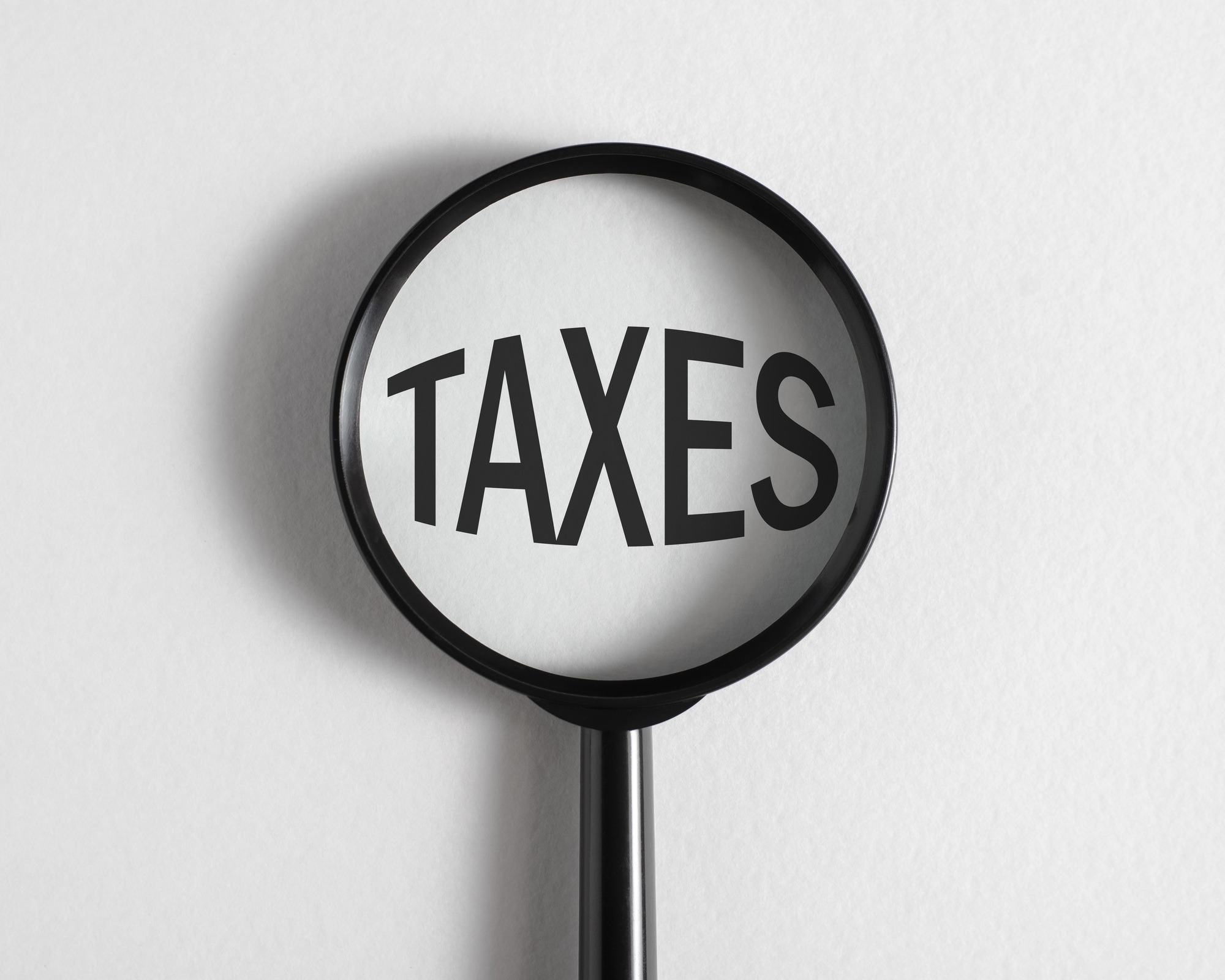 Tax increase, financial, economic concept. Magnifying glass focused on big word Taxes