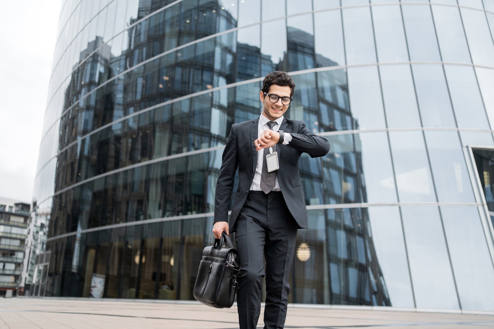 The manager looks at the clock a man with glasses goes to the office to work, in a business suit