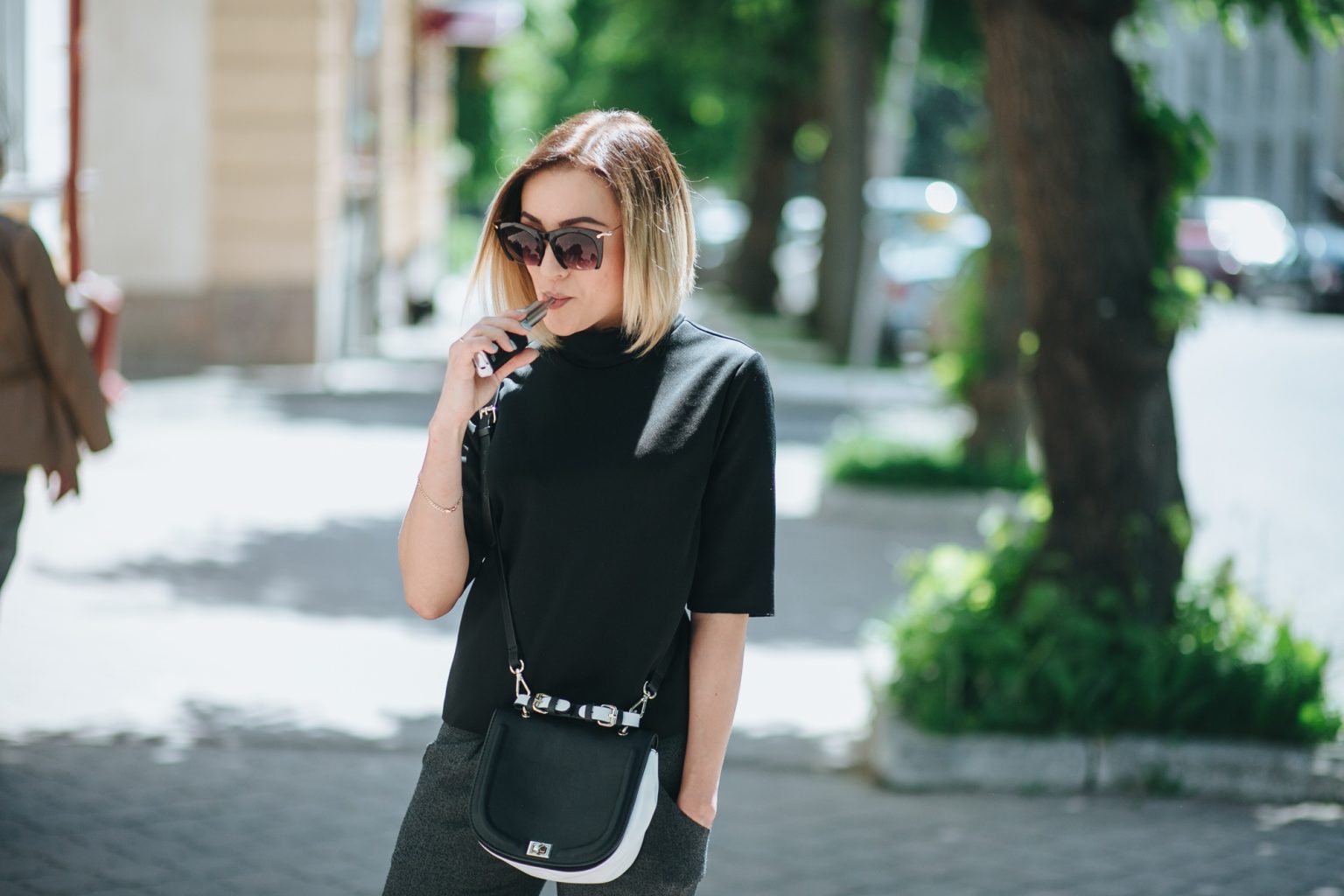 young blonde outside uses fashionable and healthy e-cigarette