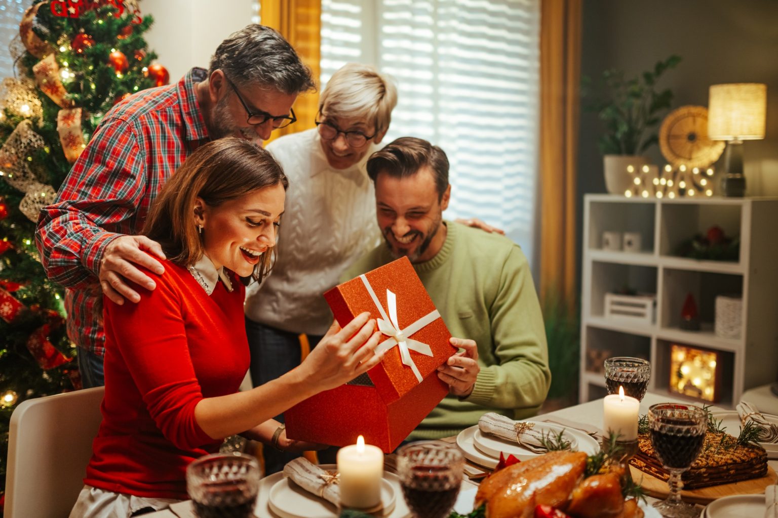 Happy family opening christmas present at dinner table