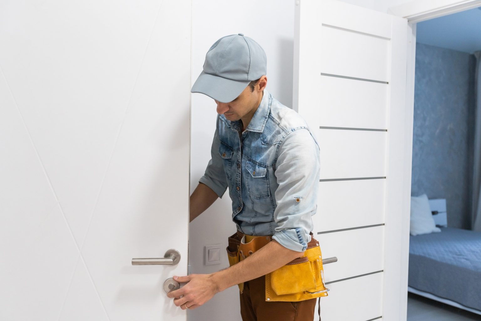 Installation of a lock on the front wooden entrance door. Portrait of young locksmith workman