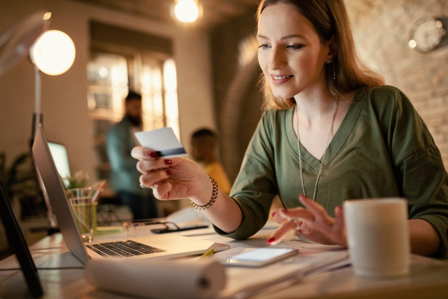 Young businesswoman using credit card and mobile phone for online banking in the office.