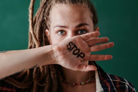 Close-up of a woman holding her hand marked with 'stop' in front of her face, symbolizing protest and strength.