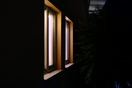 Two lit windows on a dark building exterior.