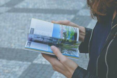 Changement d’adresse aux impôts : les 3 méthodes officielles pour éviter les majorations en 2026 A person flipping through a travel book outdoors, showcasing a variety of vibrant pages.