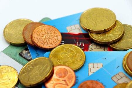 Peut-on emprunter après 60 ans pour un achat immobilier ? Close-up image of Euro coins and credit cards representing modern financial transactions.
