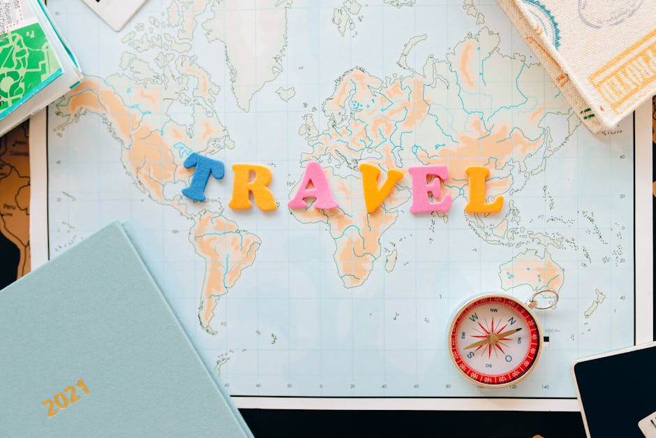 État des lieux : les 7 erreurs qui vident votre dépôt de garantie Flat lay of a map with colorful letters "TRAVEL" and a compass for planning adventures.