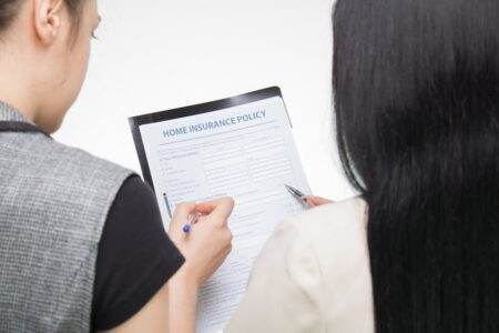 Luko et l’assurance immeuble : vraie révolution ou simple rabotage de primes pour les copropriétés ? Two women examining home insurance policy form, focused on details.