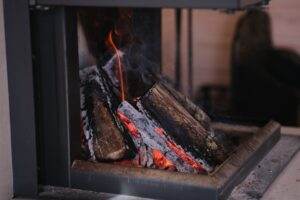 A close-up view of firewood burning in a modern indoor fireplace, emitting warmth.