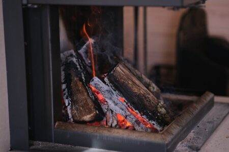 A close-up view of firewood burning in a modern indoor fireplace, emitting warmth.