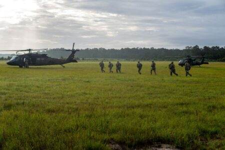 Données personnelles JeChange : ce que le site collecte vraiment et ce que vous pouvez exiger Soldiers in camouflage gear walk across a grassy field beside military helicopters.