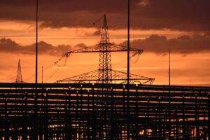 Silhouetted electric tower against vivid sunset sky, highlighting urban infrastructure.