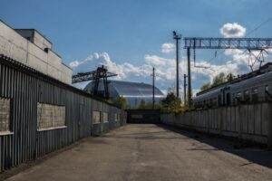 View of Chernobyl's new safe confinement and railway tracks under a blue sky.