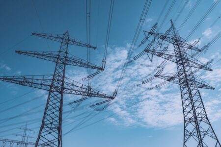 Réseau électrique européen vulnérable : 55 % du système exposé au risque de blackout, selon Ember High voltage transmission towers stretch across a clear blue sky, symbolizing energy and industry.