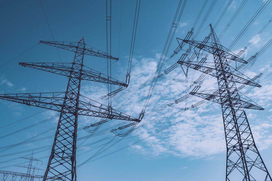 Réseau électrique européen vulnérable : 55 % du système exposé au risque de blackout, selon Ember High voltage transmission towers stretch across a clear blue sky, symbolizing energy and industry.